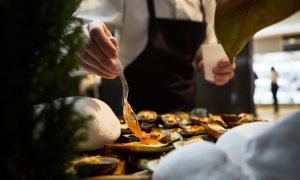 waiter adding sauce on mussels during catering